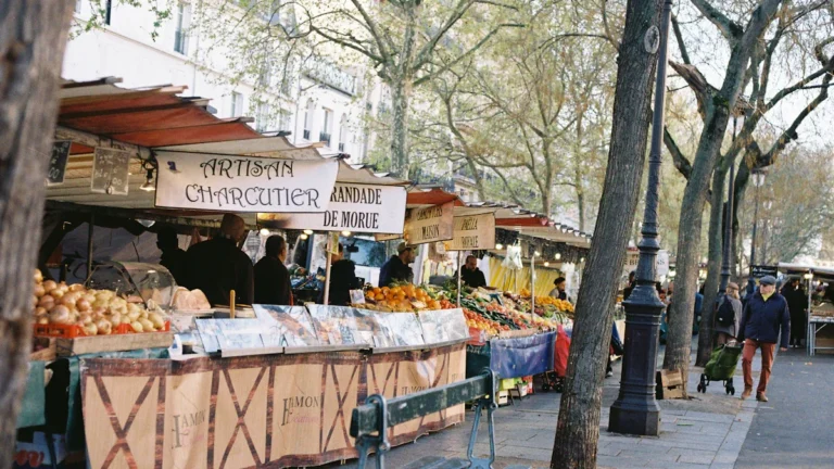 Un stand de charcuterie artisanale sur un marché en plein air à Aix-en-Provence sous les platanes.