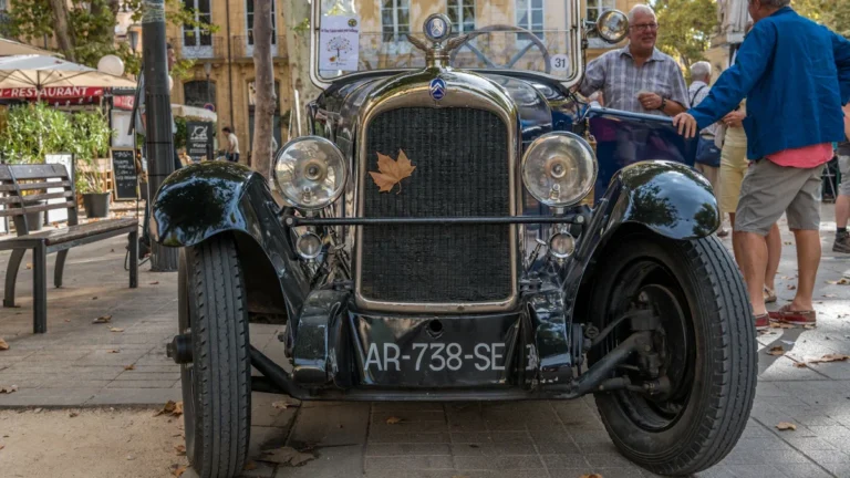 Une voiture de collection ancienne garée sur une place pavée à Aix-en-Provence.