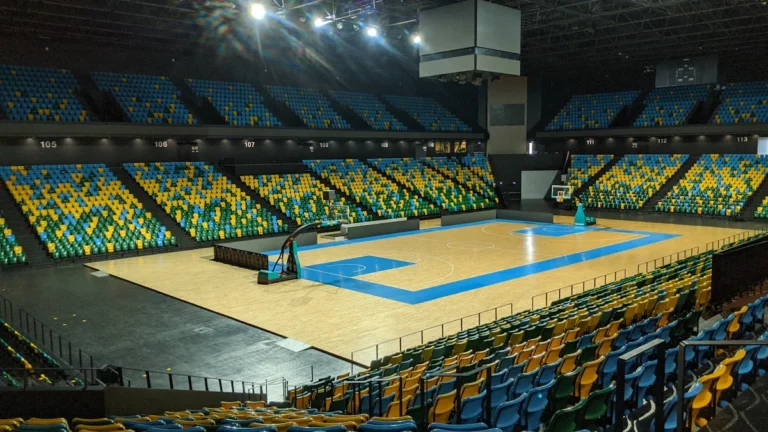 Intérieur d'un complexe sportif moderne à Nanterre avec un terrain de basket et des tribunes colorées prêtes pour le public.