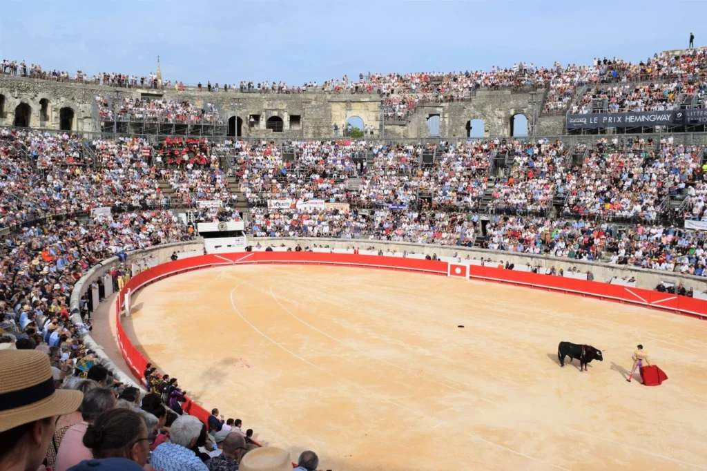 Matador face à un taureau noir dans une arène romaine comble lors d'une corrida ensoleillée.