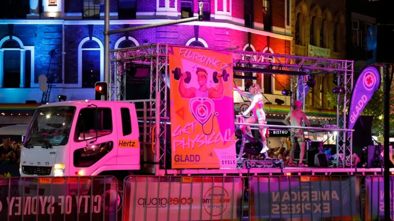 Un char de parade illuminé de rose circulant en ville la nuit, illustrant l'ambiance festive du retour des associations à Caen.