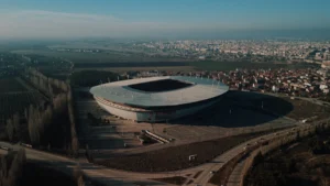 Une vue aérienne spectaculaire d'un stade de football entouré par le paysage urbain en fin de journée.