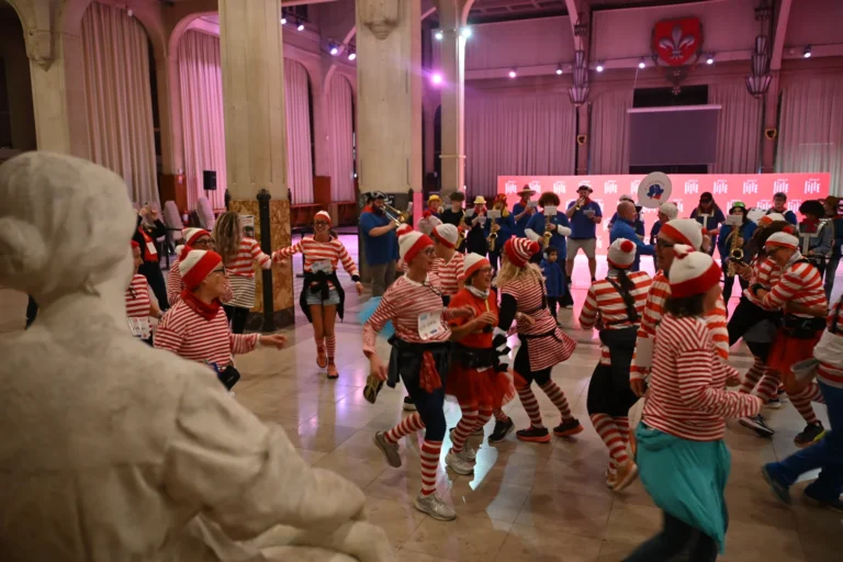 Foule déguisée en Charlie portant des rayures rouges et blanches dansant dans une grande salle.