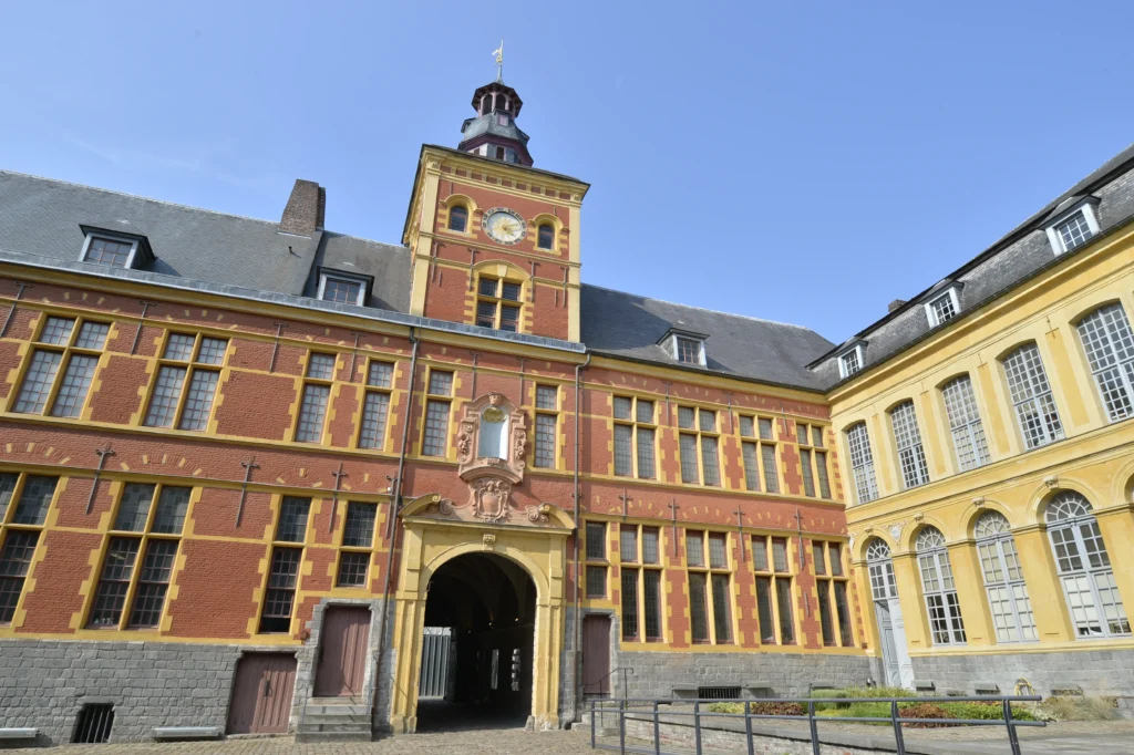 Bâtiment historique en briques rouges et pierres jaunes avec une tour d'horloge centrale.