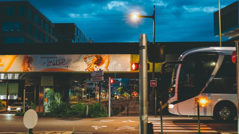 Une rue moderne à Metz à la tombée de la nuit montrant un bus de transport en commun et des aménagements urbains.