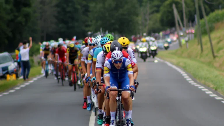 Un peloton de cyclistes professionnels en pleine course sur une route de campagne lors du Tour de France.