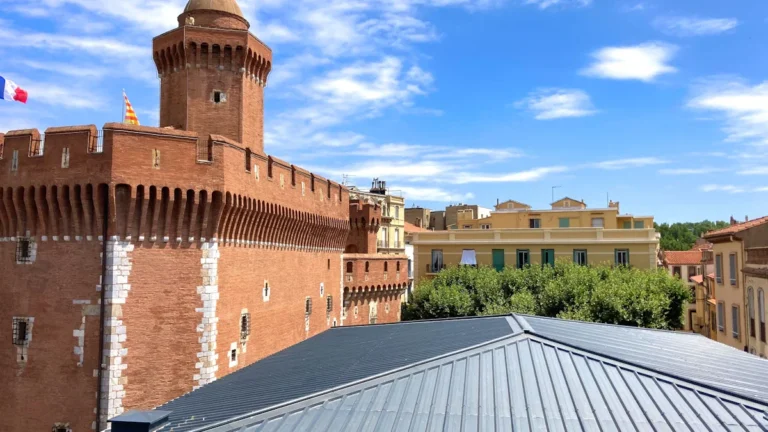 Le Castillet, monument emblématique en briques rouges sous un ciel bleu à Perpignan.