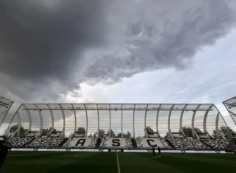 Vue d'un stade de football avec des tribunes vides sous un ciel d'orage très sombre.