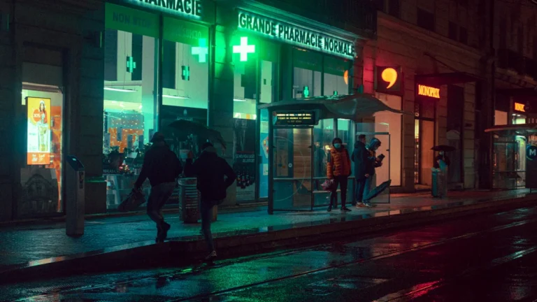 Une pharmacie française éclairée de nuit, illustrant l'accès aux soins de santé en milieu urbain.