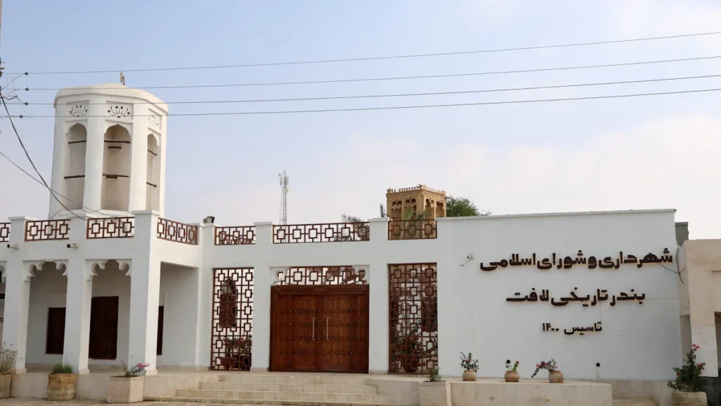 Façade d'un bâtiment blanc avec une tour ornée et des inscriptions calligraphiques en arabe.
