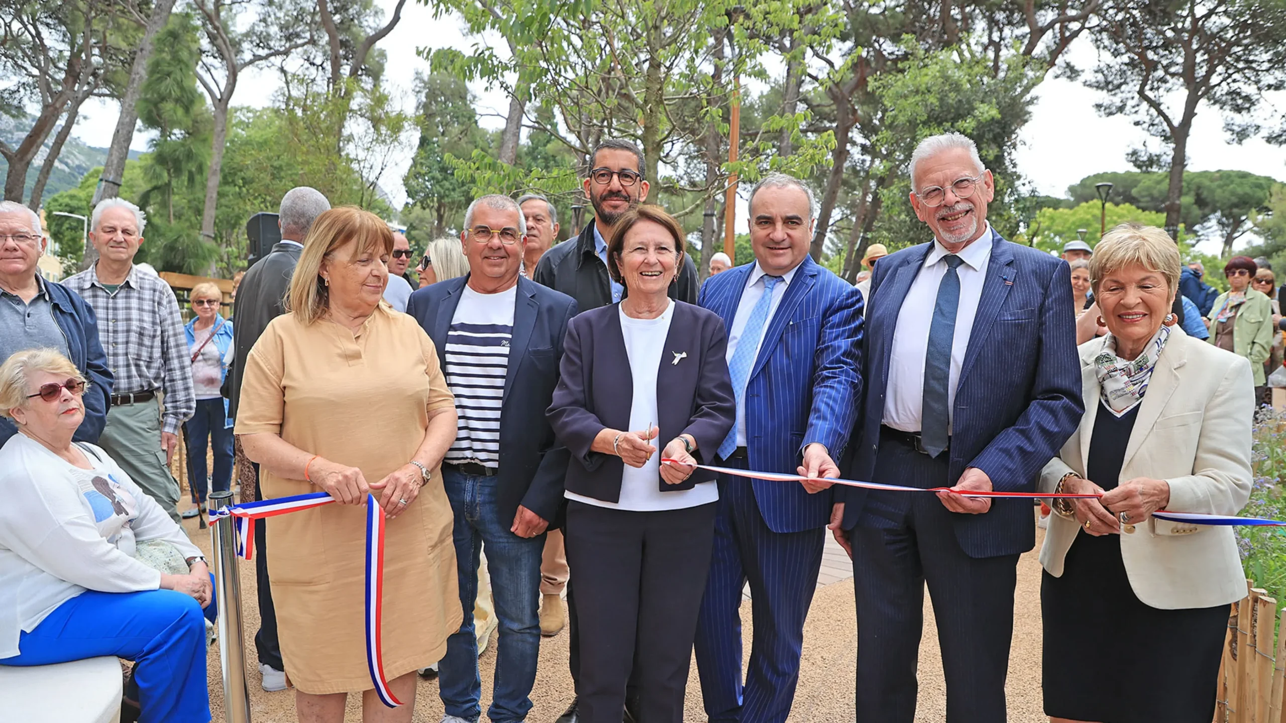 Plusieurs officiels coupent un ruban tricolore lors de l'inauguration d'un nouvel espace vert extérieur.