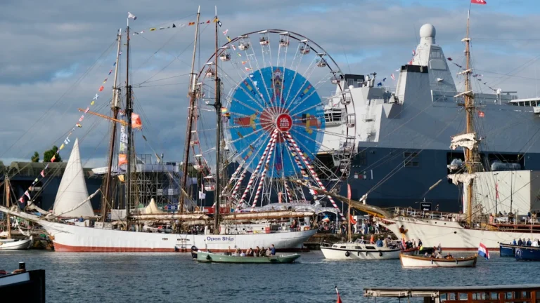 Un voilier de légende amarré à côté d'un navire de la Marine nationale et d'une grande roue lors d'un rassemblement maritime à Toulon.