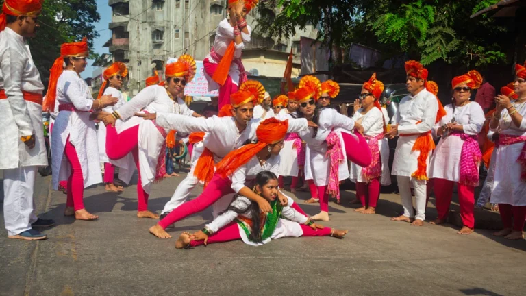 Un groupe de danseurs indiens en costumes traditionnels blancs et roses effectue une chorégraphie dynamique lors d'un festival de rue célébrant la culture mondiale.