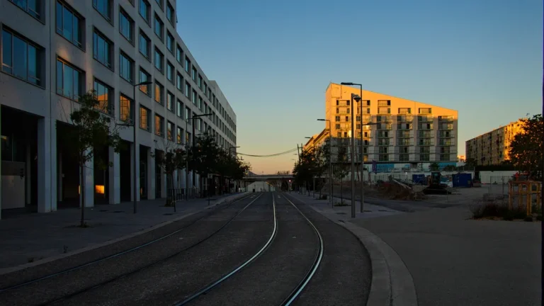 Rails de tramway s'étendant entre des immeubles modernes sous un ciel matinal dégagé.