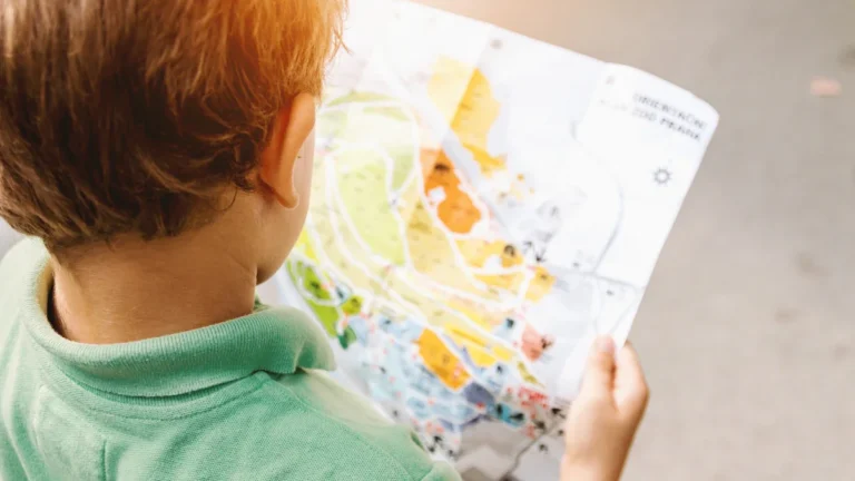 Un jeune garçon regarde attentivement une carte lors d'une chasse aux trésors en extérieur.