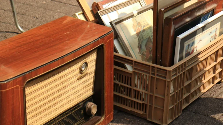 Une radio ancienne en bois et des cadres de tableaux dans une caisse au vide-greniers.
