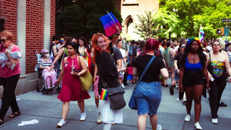 Une foule de manifestants défile avec des drapeaux colorés lors de la Marche des Fiertés, symbolisant 20 ans d'engagement.