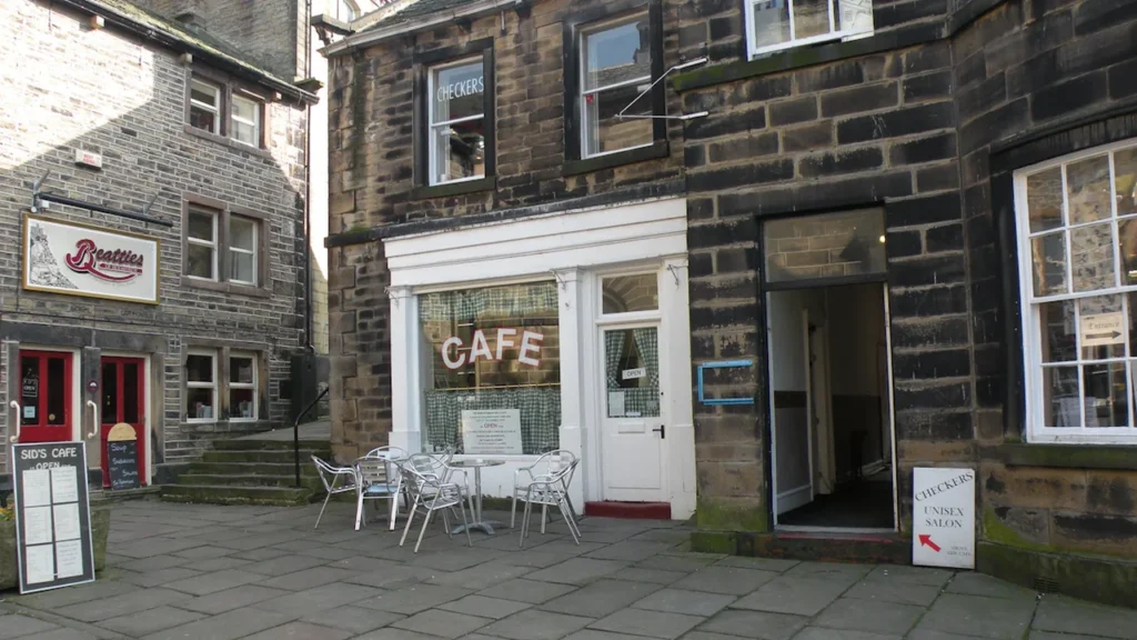 Façade en pierre d'un café convivial accueillant des visiteurs en terrasse extérieure.