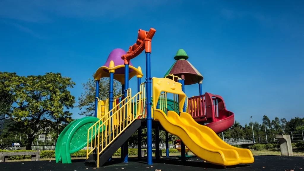Structure de jeu colorée pour enfants avec toboggans dans un parc public ensoleillé.