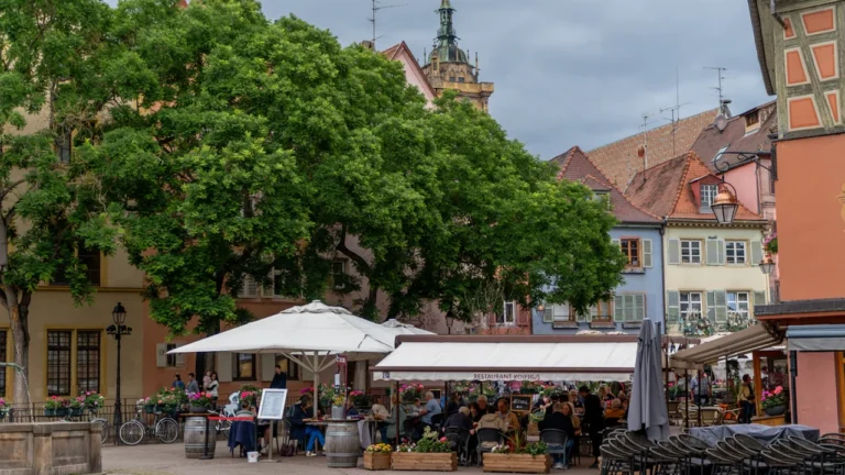 Une terrasse de café animée dans une rue historique de Colmar, en France.