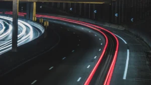 Longue exposition montrant le trafic urbain sur une autoroute éclairée la nuit.