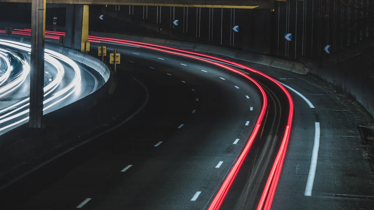 Longue exposition montrant le trafic urbain sur une autoroute éclairée la nuit.