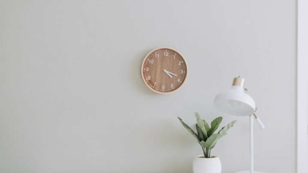 Une lampe de bureau minimaliste et une plante verte sur un espace de travail épuré.