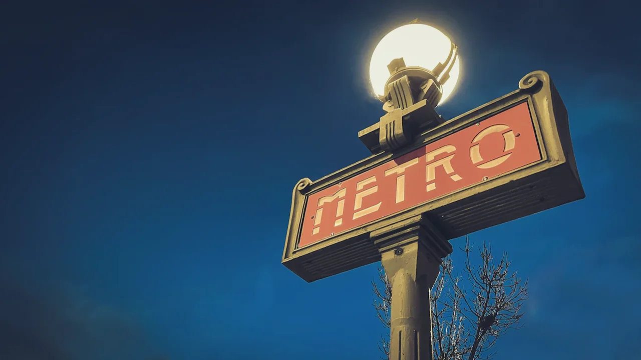 Panneau signalétique typique du métro parisien sous un ciel bleu.