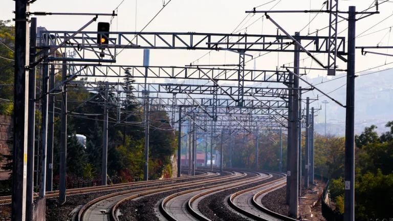 Vue d'ensemble d'une voie ferrée électrifiée avec ses caténaires métalliques.
