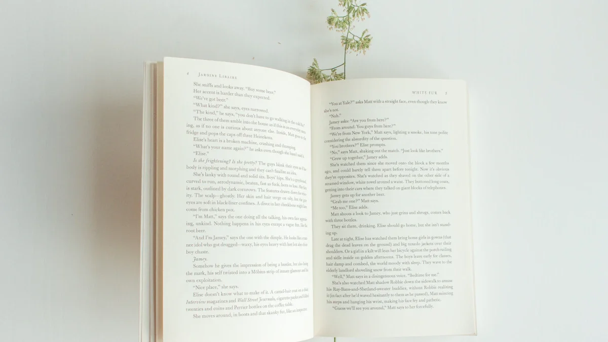 Un livre ouvert posé sur une table avec une plante verte délicate.