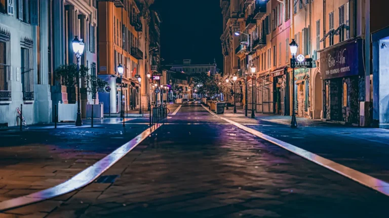 Une rue urbaine européenne calme et éclairée la nuit par des réverbères.