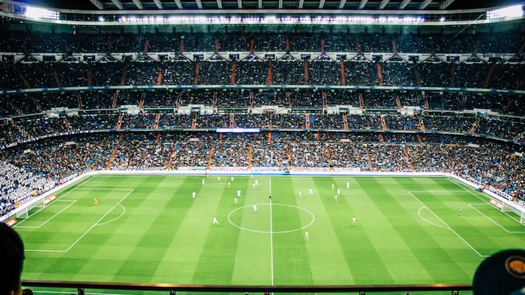 Vue panoramique d'un stade de football rempli lors d'un grand événement sportif nocturne.