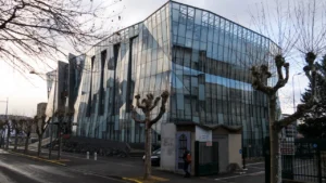 Façade vitrée moderne d'un bâtiment emblématique dans une rue de Clermont-Ferrand.