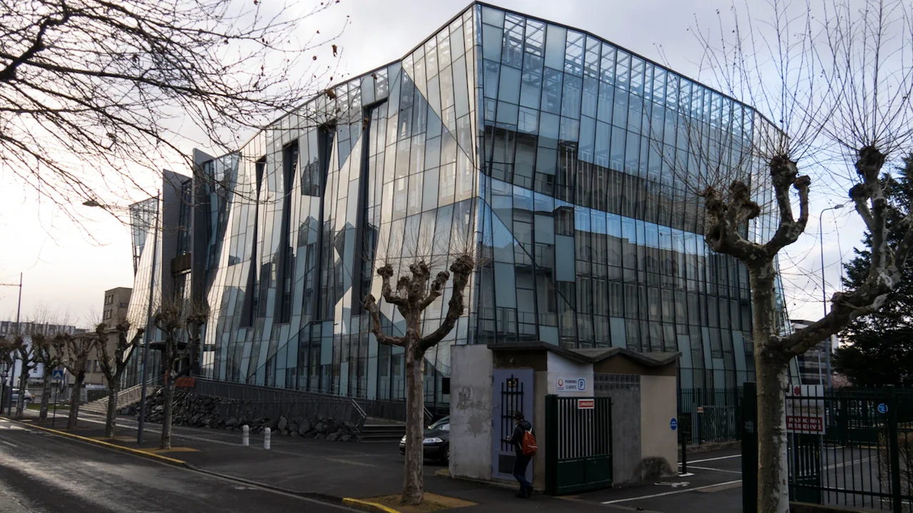 Façade vitrée moderne d'un bâtiment emblématique dans une rue de Clermont-Ferrand.