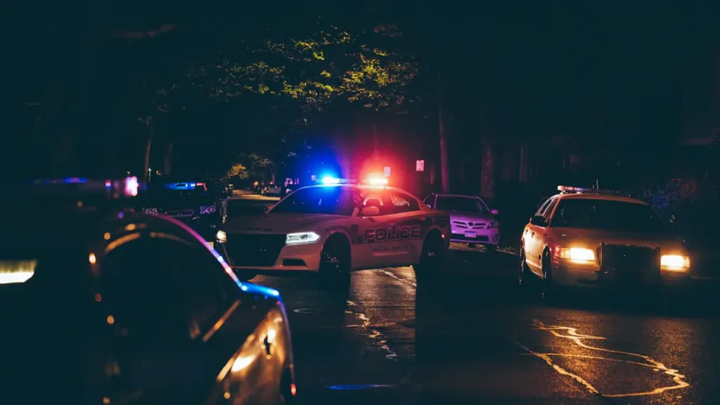 Voiture de police stationnée lors d'une intervention nocturne dans une rue sombre.