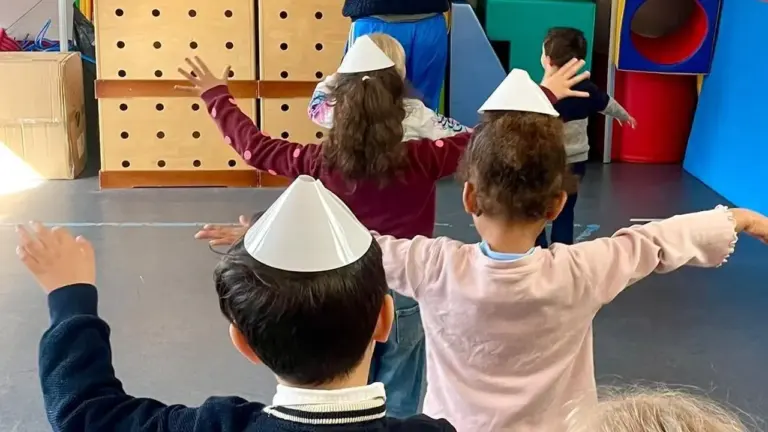 Un enseignant et plusieurs jeunes enfants portant des cônes en papier effectuent des exercices.