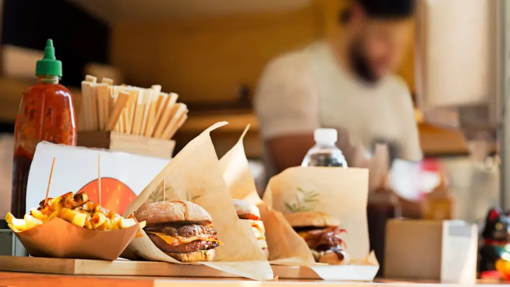 Des burgers et des frites servis dans des emballages en papier sur un comptoir.