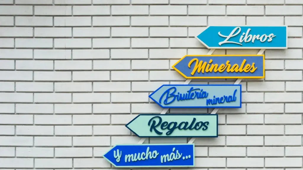 Des panneaux colorés en forme de flèches indiquant divers commerces sur un mur blanc.