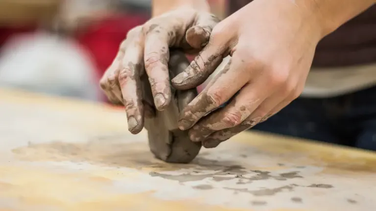 Les mains d'un potier travaillant l'argile lors d'un atelier de modelage manuel.