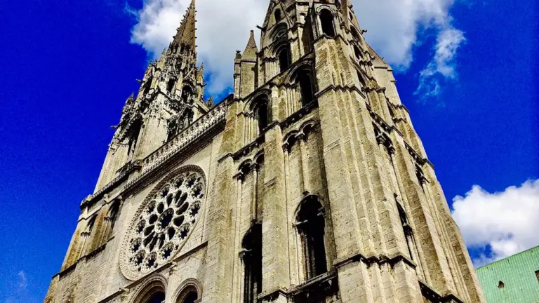 Vue emblématique des flèches de la cathédrale de Chartres sous un ciel bleu.