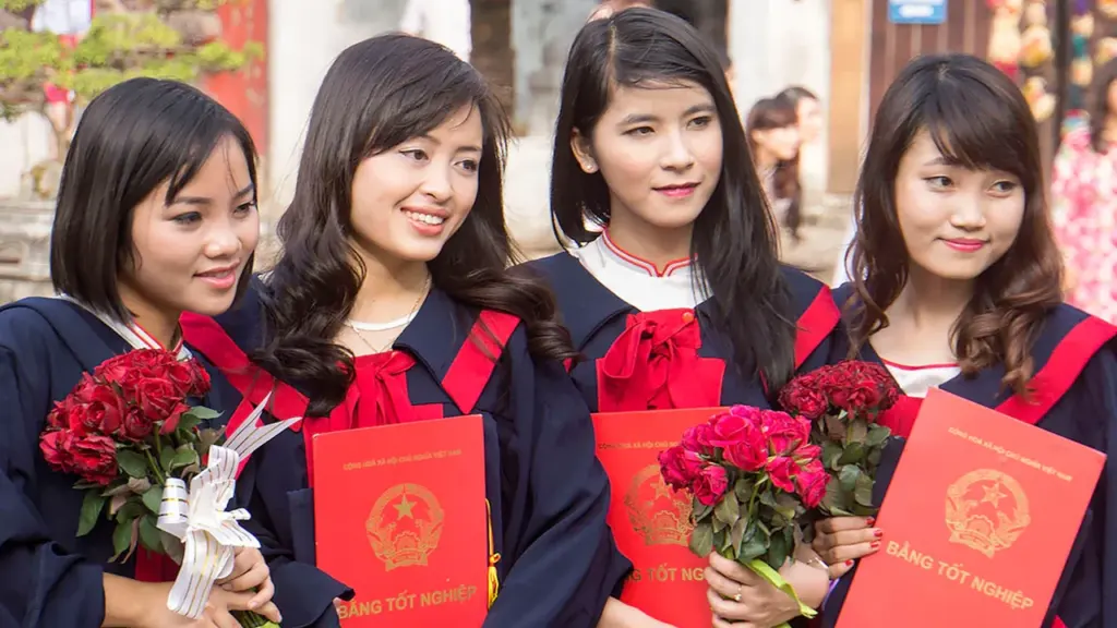 Quatre jeunes diplômées en toges tenant des fleurs et des diplômes lors d'une cérémonie.