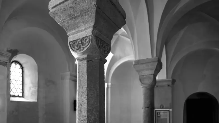 Colonnes en pierre et voûtes dans une crypte romane historique et lumineuse.